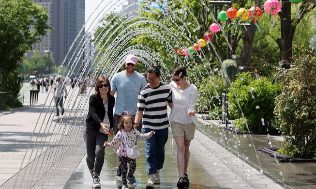 Иностранные туристы прогуливаются под фонтаном