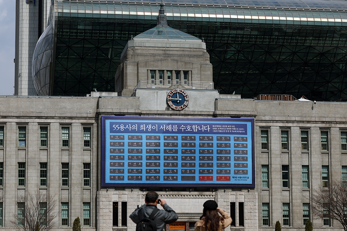 20 марта, за два дня до девятой годовщины Дня защиты Желтого моря, горожане делают фото плаката с именами 55 воинов, вывешенного на внешней стене Сеульской библиотеки.