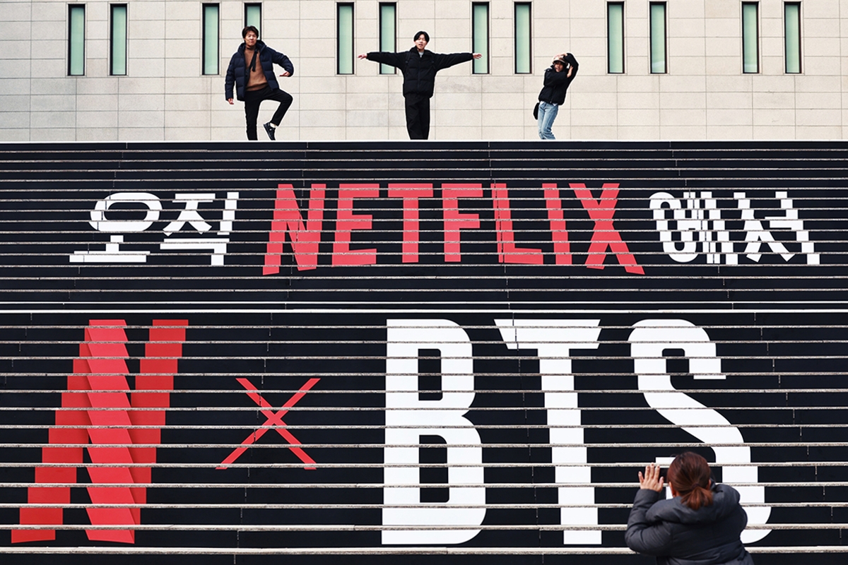 Администрация Сеула пообещала приложить максимум усилий, чтобы иностранные туристы смогли безопасно и комфортно насладиться концертом группы BTS на площади Кванхвамун 21 марта. На фото иностранные туристы 11 марта позируют для снимка на фоне лестницы Центра исполнительских искусств Седжон, украшенного в честь концерта. / Фото: Рёнхап 