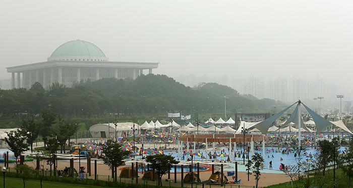5일 국회의사당을 배경으로 삼은 여의도 한강공원 수영장을 찾은 사람들이 물놀이를 즐기고 있다. 전한 기자
