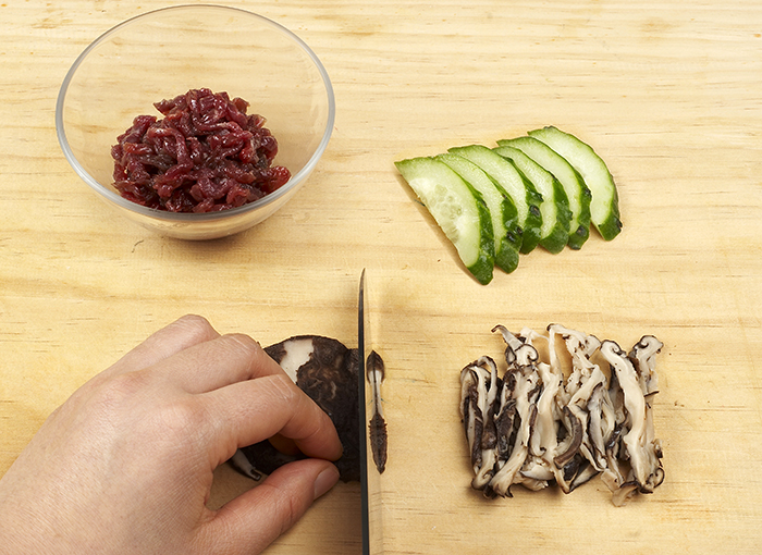 Cucumbers, beef and shitake mushrooms are needed to prepare bibim guksu. All the ingredients need to be cut into small pieces and marinated.