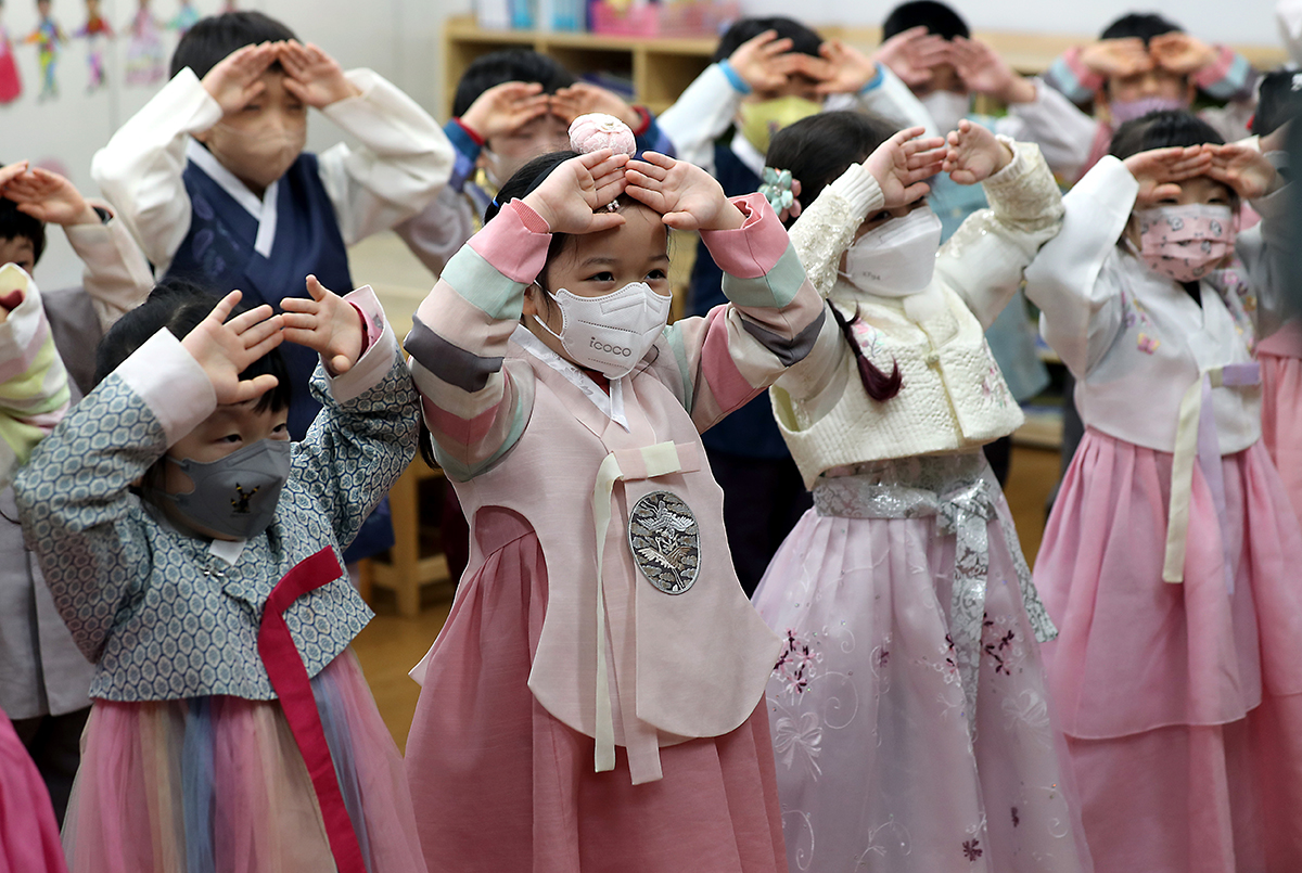 Дети в ханбоках 12 января учатся делать поклоны в детском саду в районе Пусанчжин-гу.