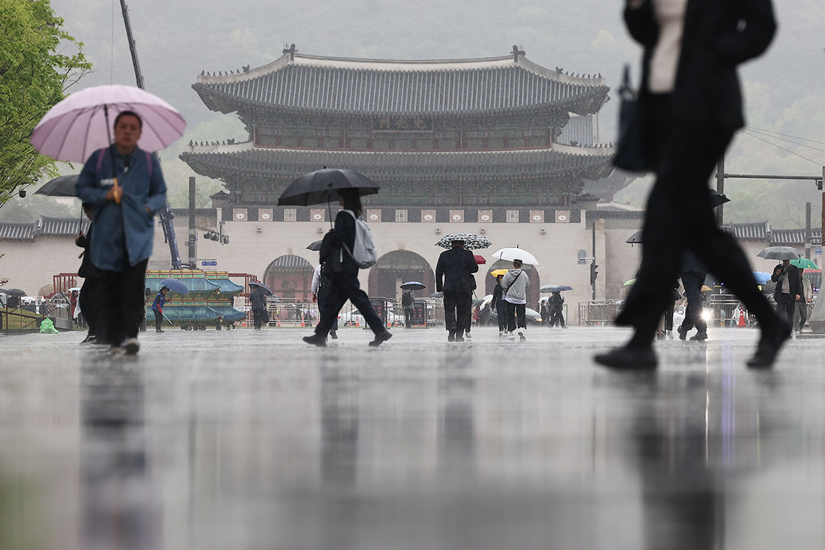 15 апреля горожане с зонтами прогуливаются по площади Кванхвамун в центре Сеула.