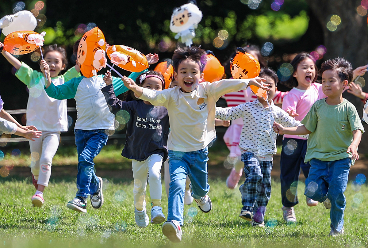 2 апреля, за три дня до Дня защиты детей, дети играют с мыльными пузырями на свежем воздухе перед музеем Хансон Пэкче в Олимпийском парке в Сонпха-гу в Сеуле. 