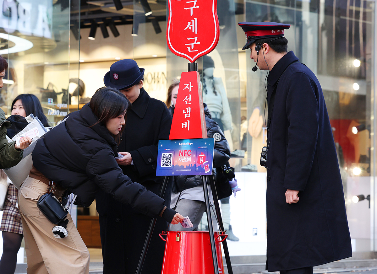 28 ноября девушка делает пожертвование в благотворительный фонд Армии Спасения на улице Мёндон в районе Чун-гу в Сеуле.