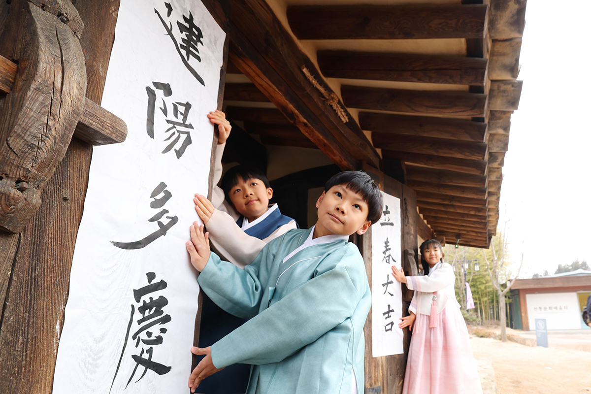 4 февраля, в день &laquo;ипчхун&raquo;, символизирующий начало весны, дети позируют с традиционными полотнами с пожеланием удачи у главных ворот дома Очон в Национальном фольклорном музее Кореи в Сеуле.