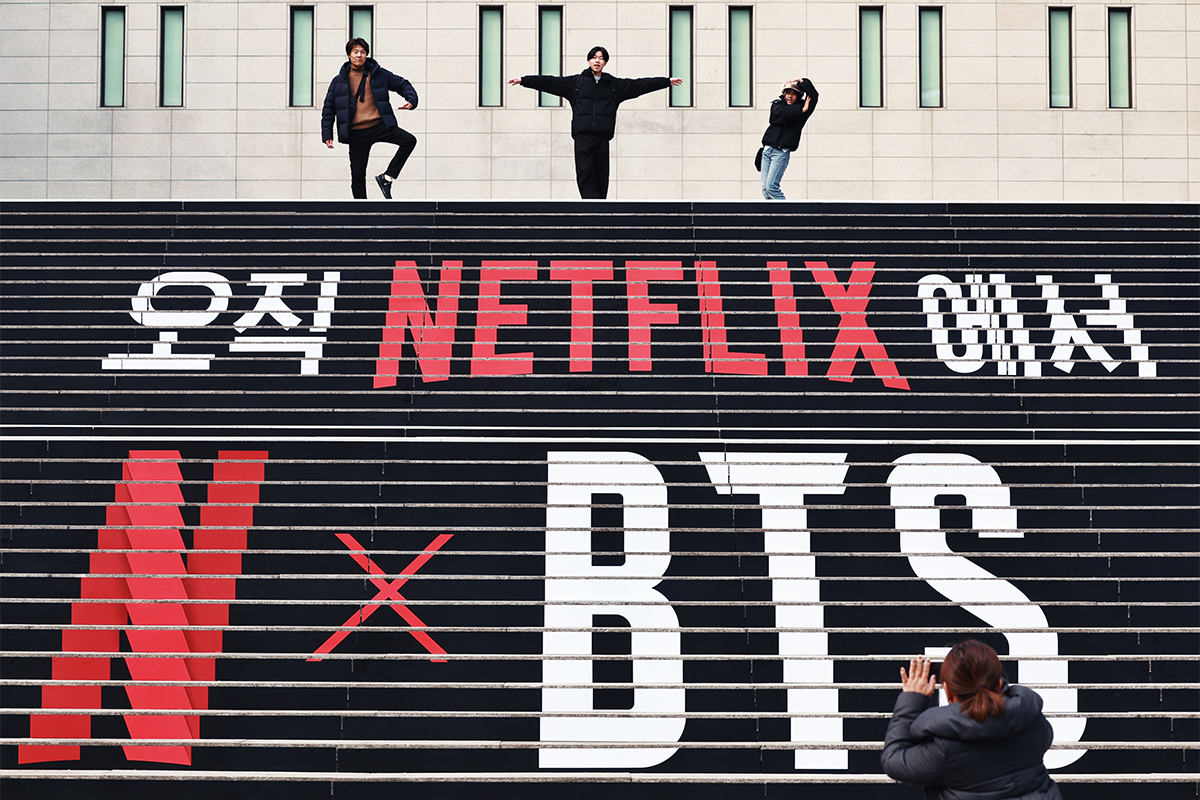 11 марта иностранные туристы позируют для фото на фоне надписи на лестнице площади Кванхвамун в Сеуле, сообщающей о скором возвращении группы BTS в полном составе.